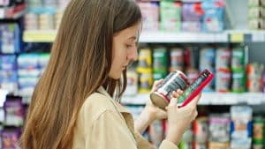 woman choosing canned cat food reading label